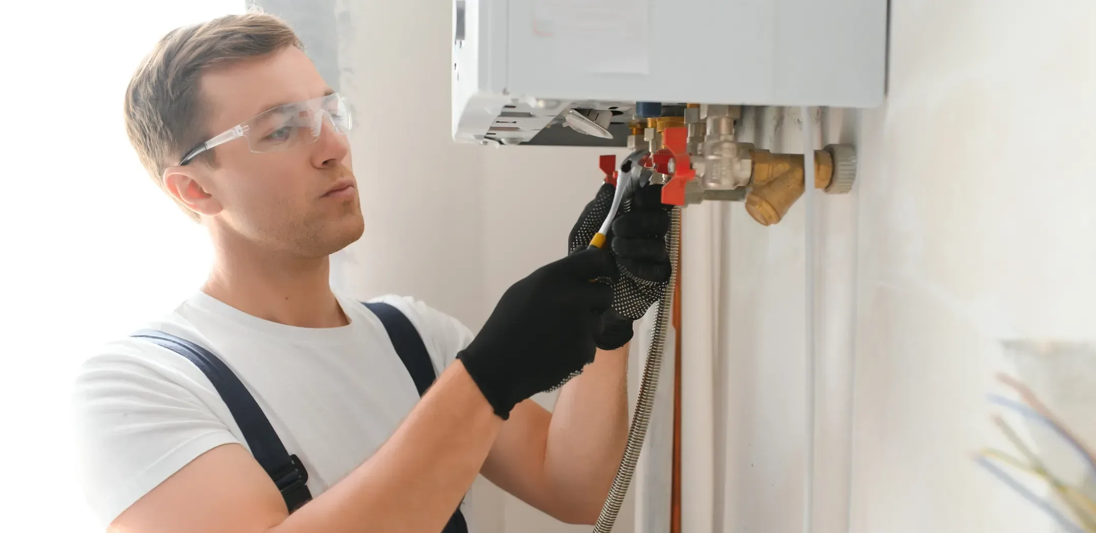 man repairing boiler on white wall